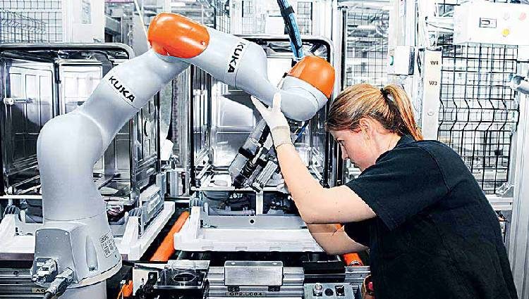 Woman and robotic machine work together inside industrial building.